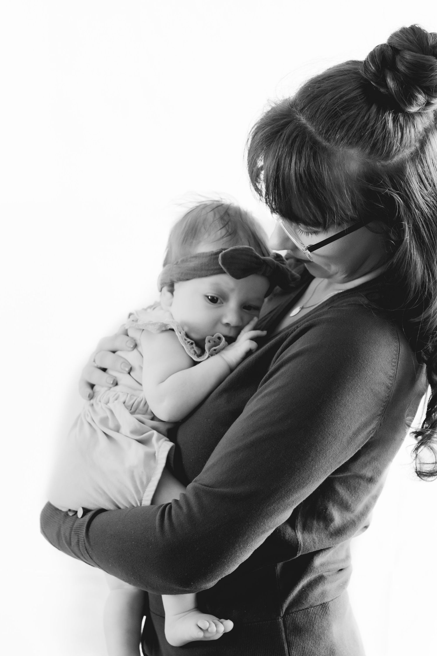 Black and white photo of parent cradling baby wearing glasses and a casual top.