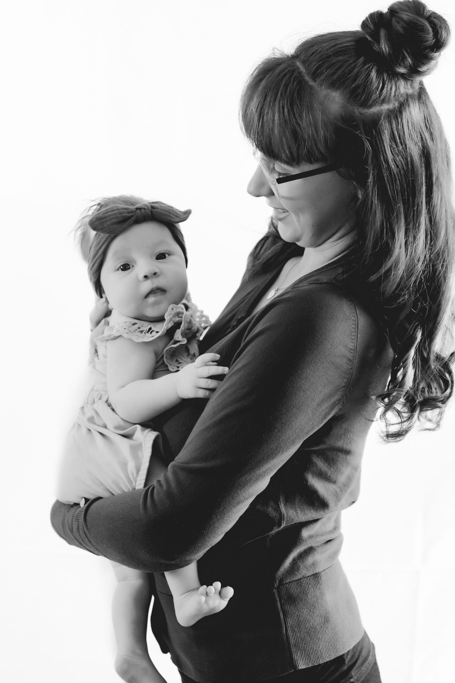 Black and white side profile of person holding a small baby wearing a headband.