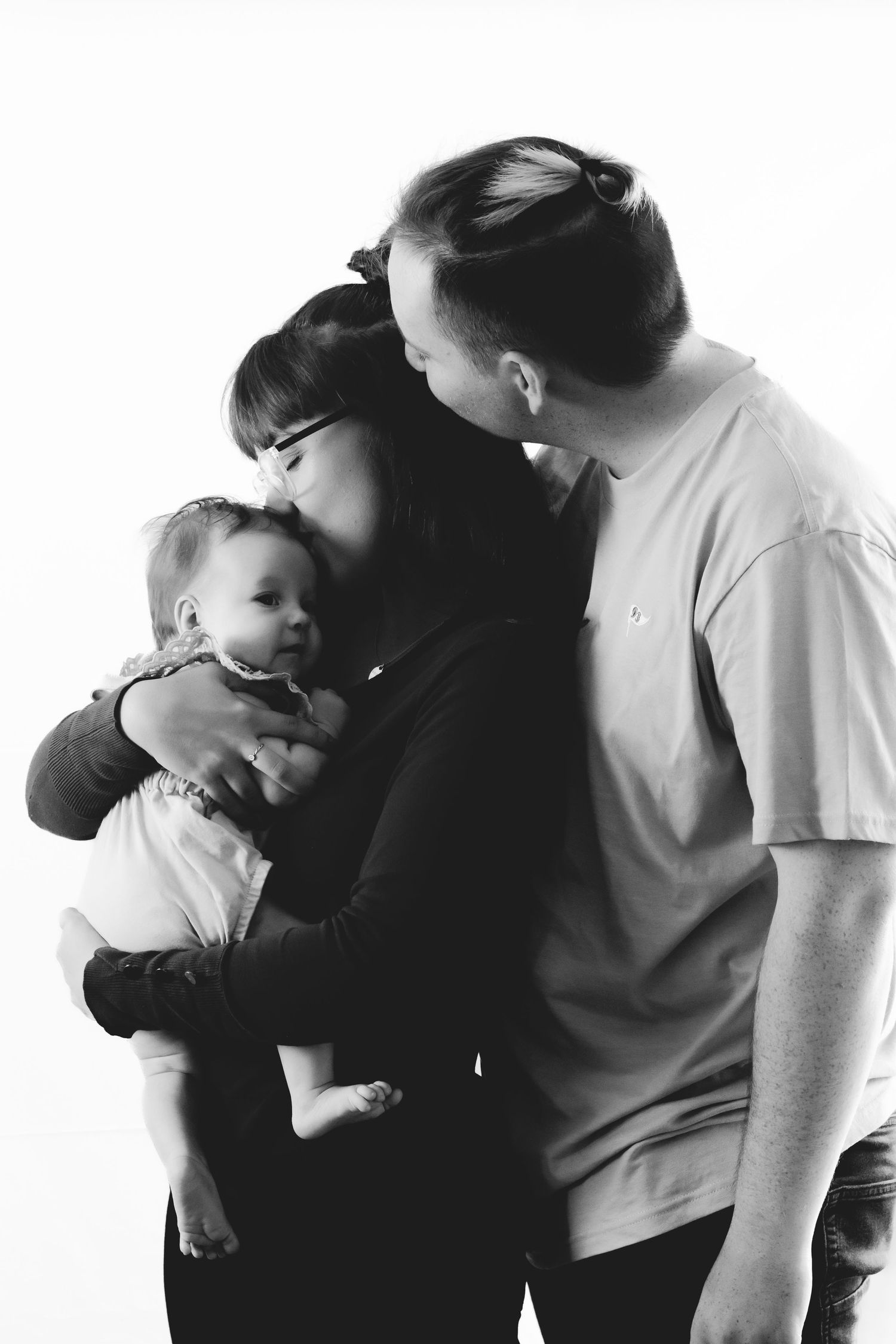 Black and white portrait of a family sharing an intimate moment with their baby.