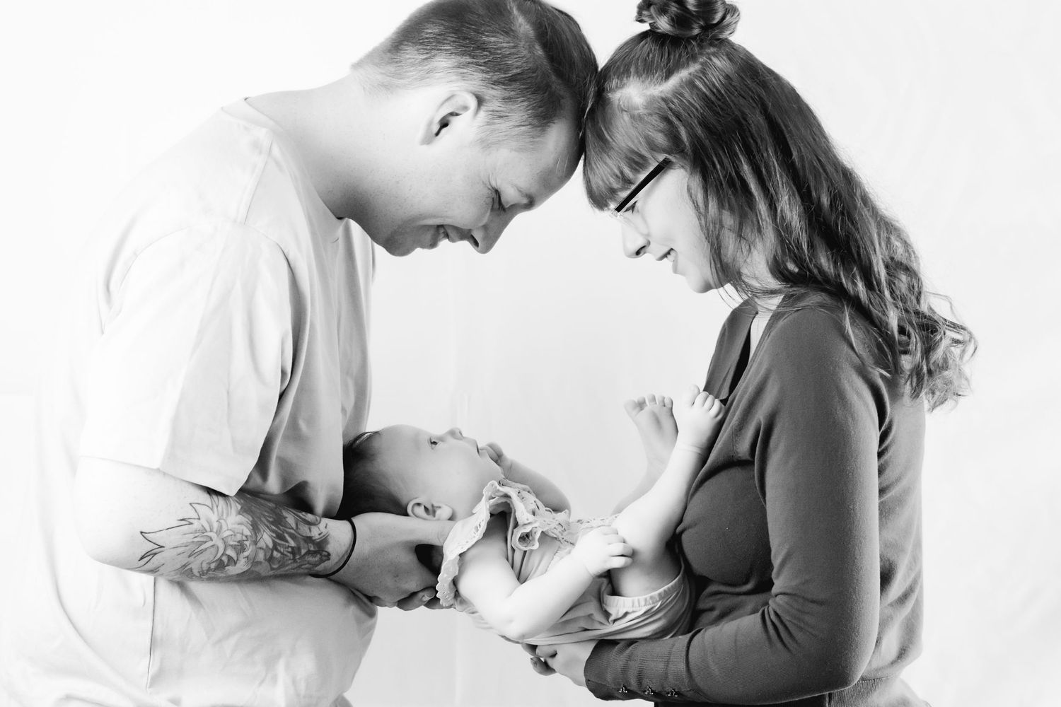 Black and white image of couple in tender moment with their newborn baby.