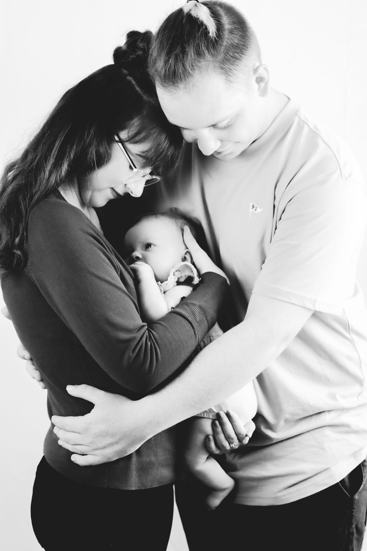 Black and white intimate portrait of parents holding their newborn baby close.