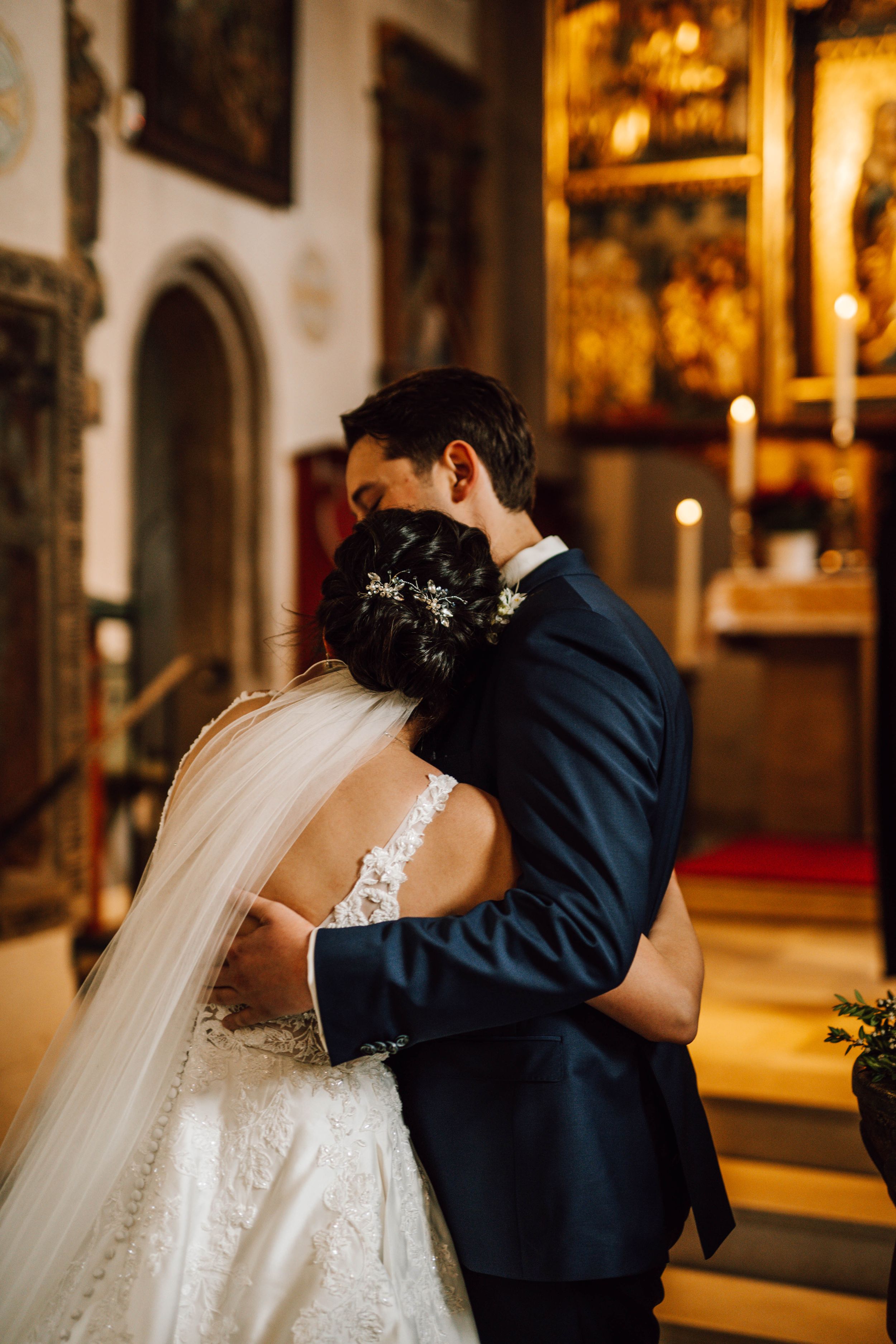 A romantic embrace captured during a wedding ceremony in a historic church.