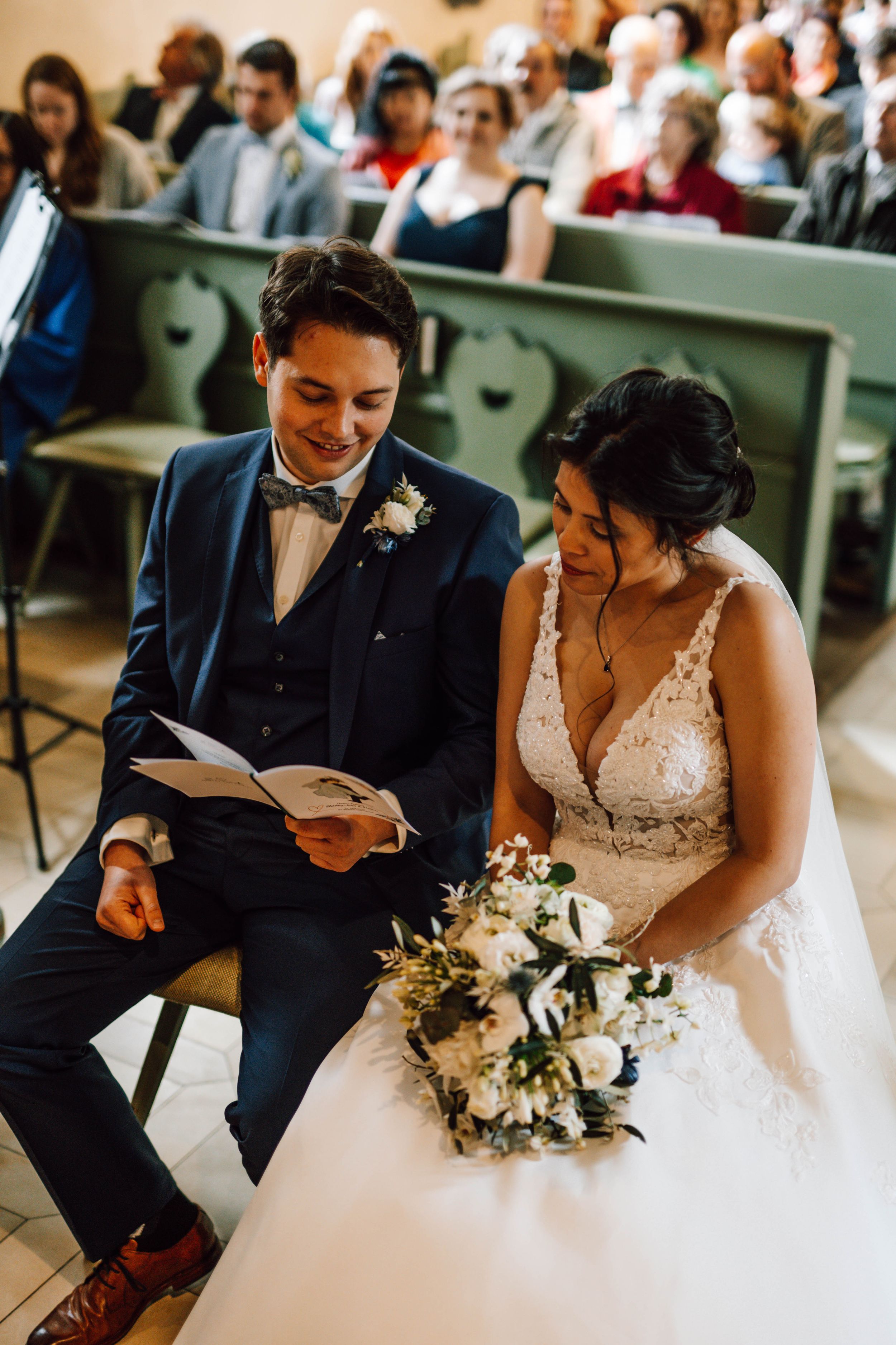 Couple sharing a moment while reading during their church wedding ceremony.