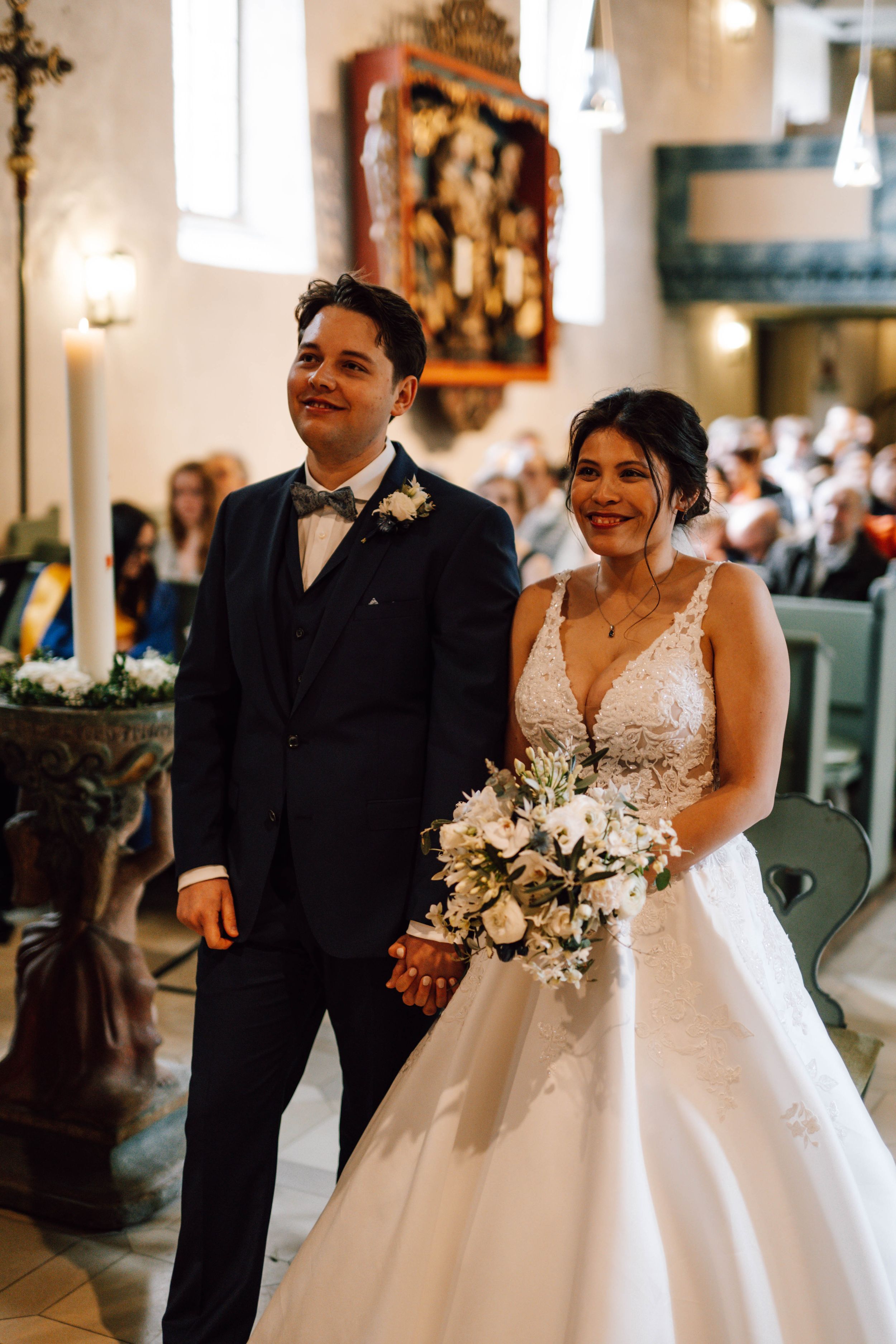 A newlywed couple laughs together during their wedding ceremony in a historic church setting.