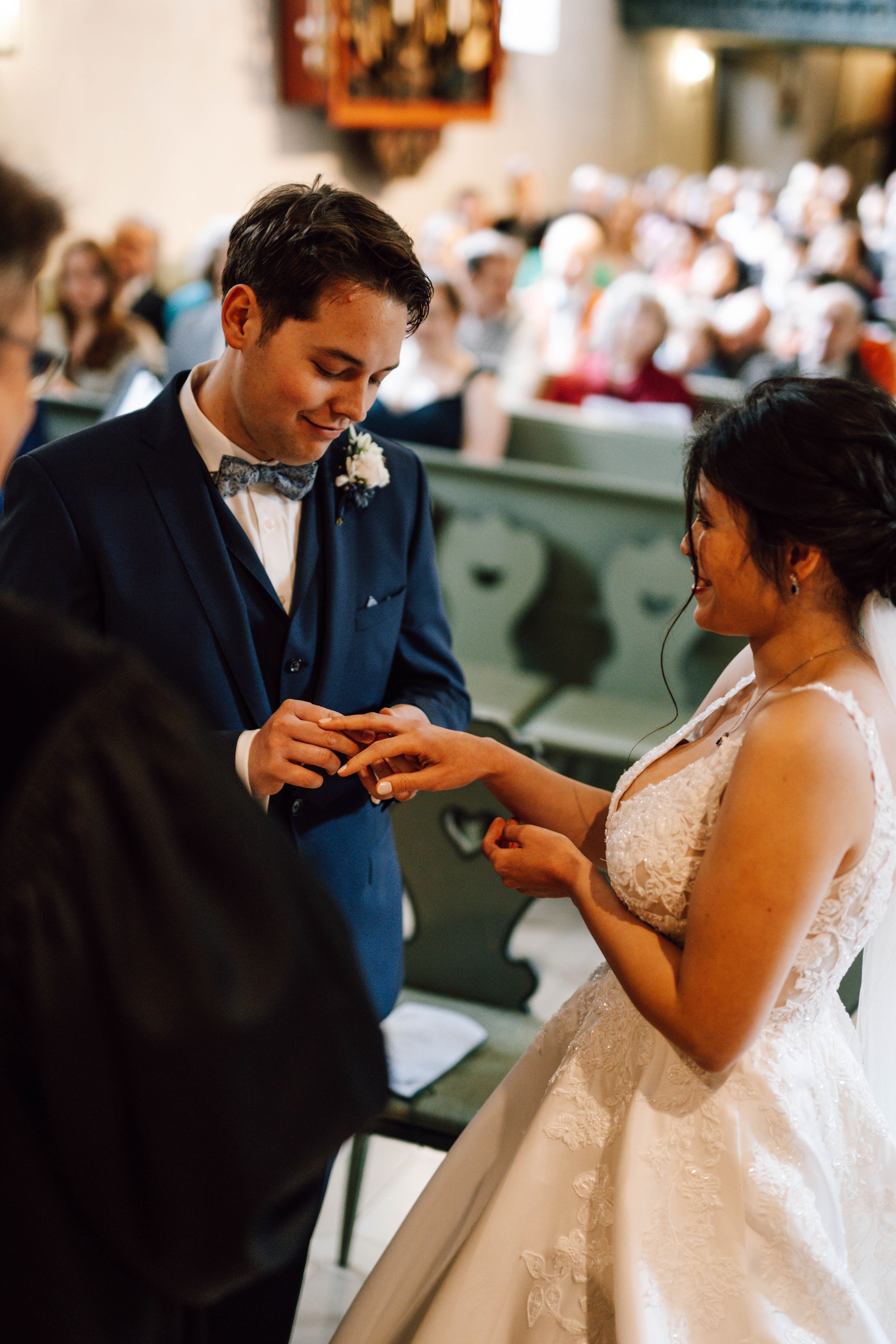 Wedding ceremony exchange of rings in a traditional church setting with beautiful interior architecture.