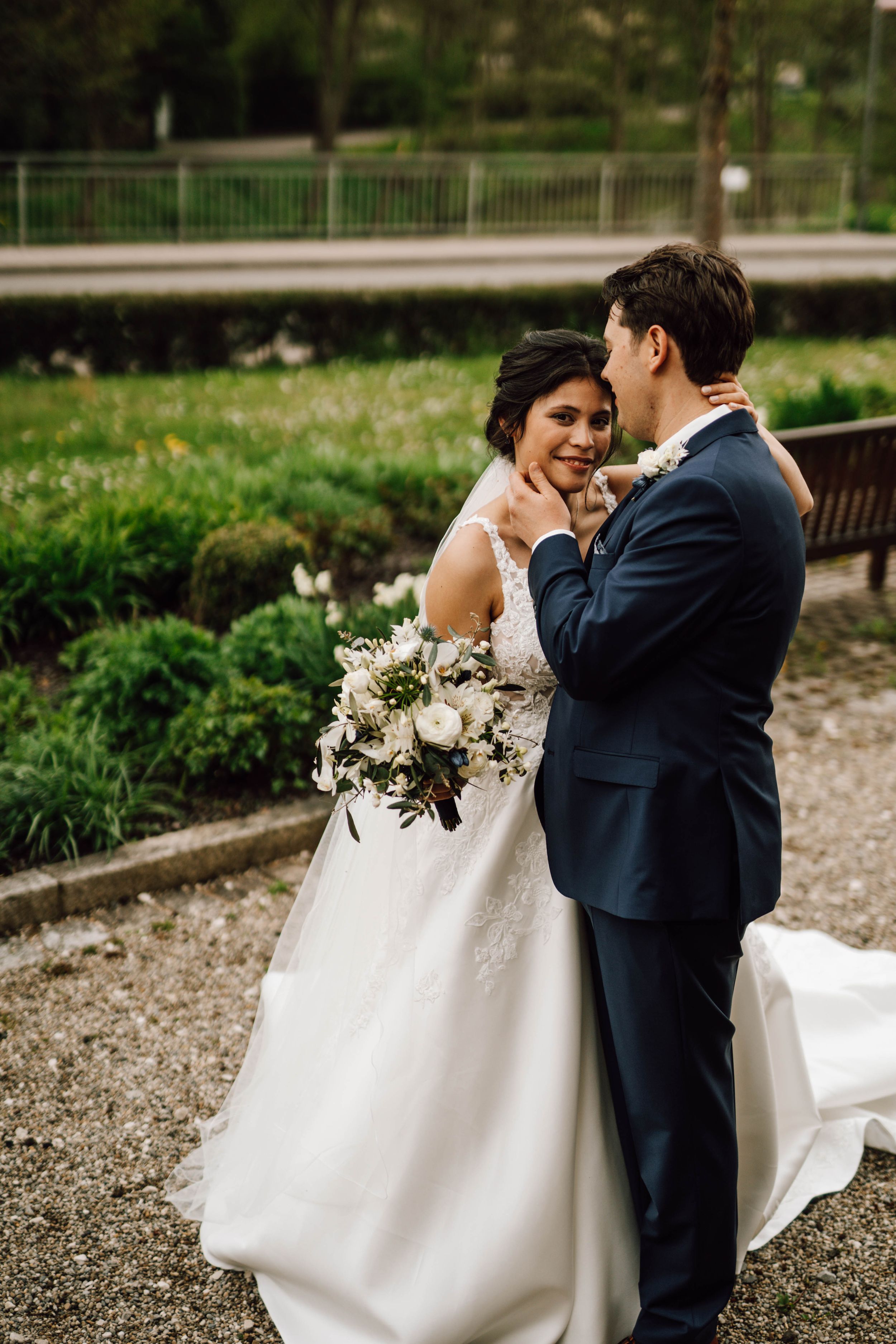 A romantic wedding portrait in a garden setting with the couple sharing an intimate embrace.