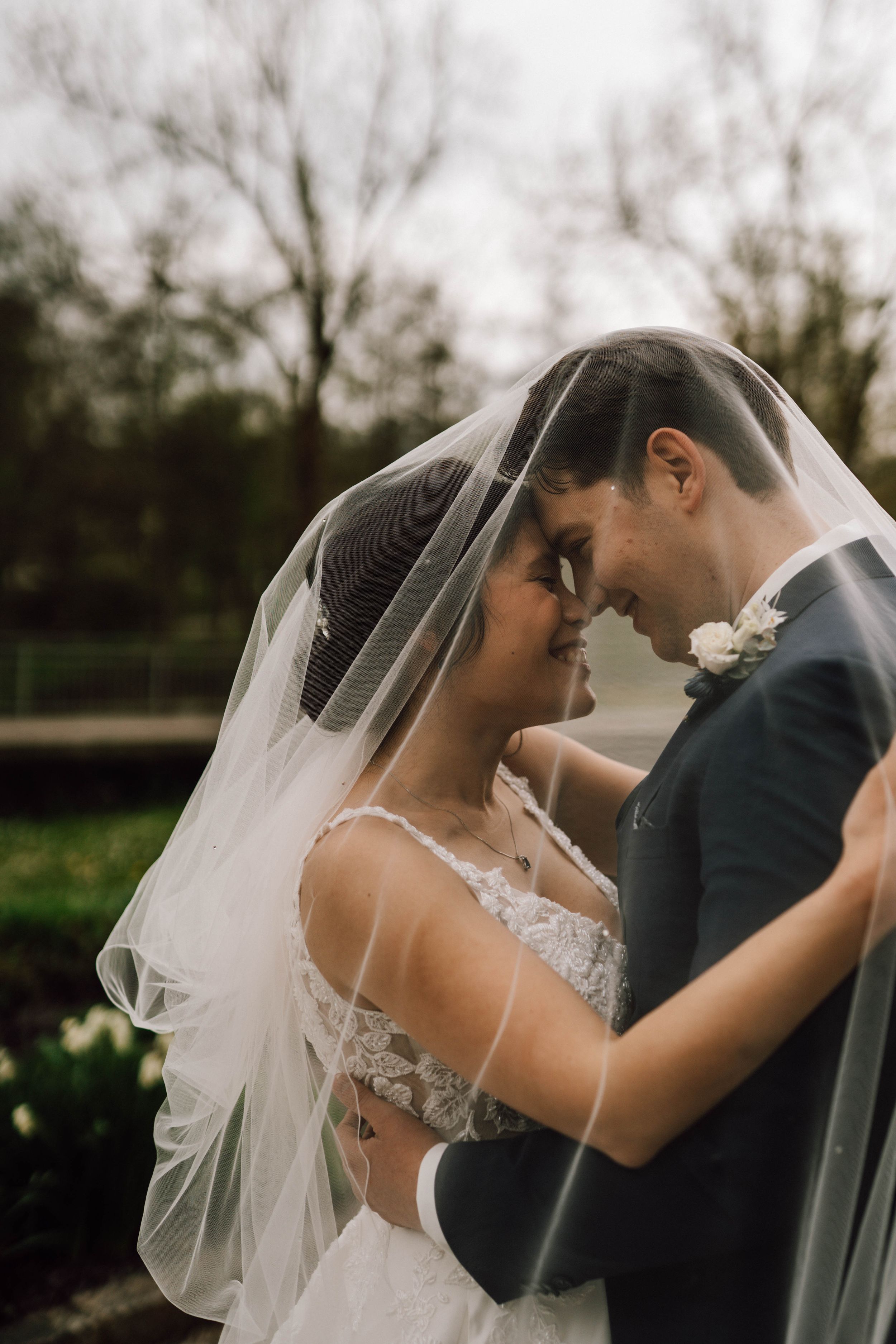 An intimate moment between newlyweds as they share a tender embrace under a flowing veil.