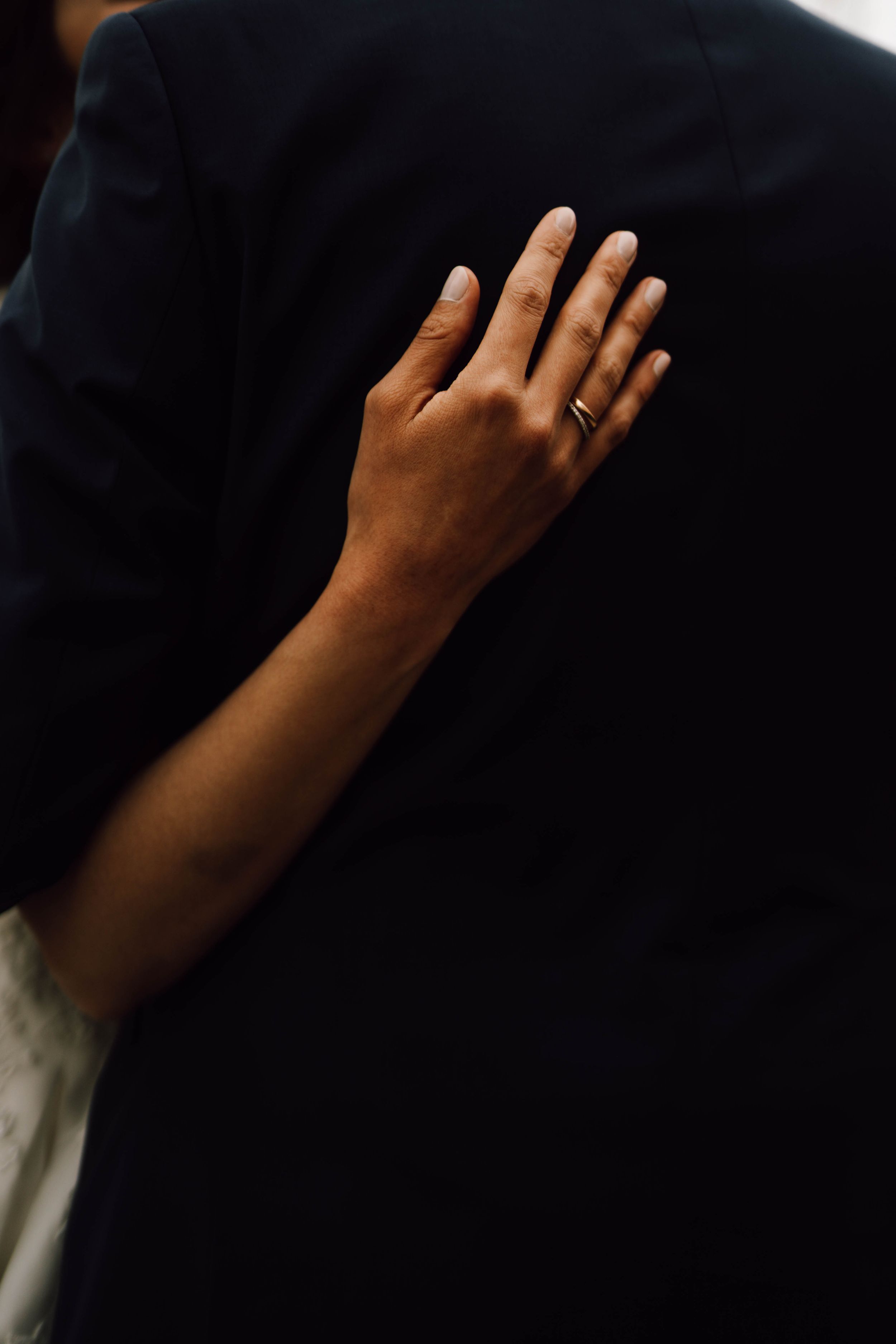 Close-up detail shots of hands against dark formal wedding attire.
