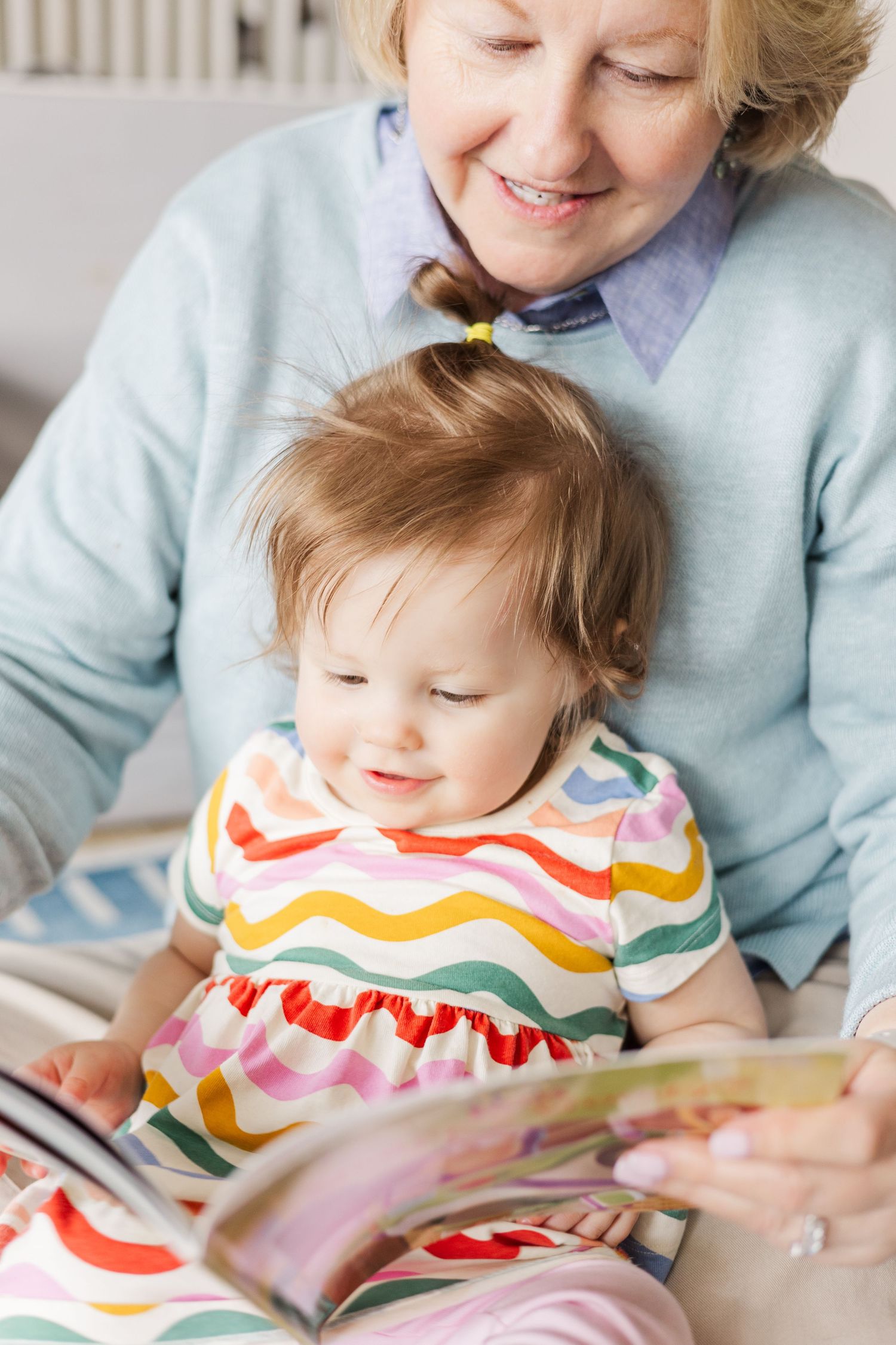 Reading time together with colorful storybook on comfortable chair.