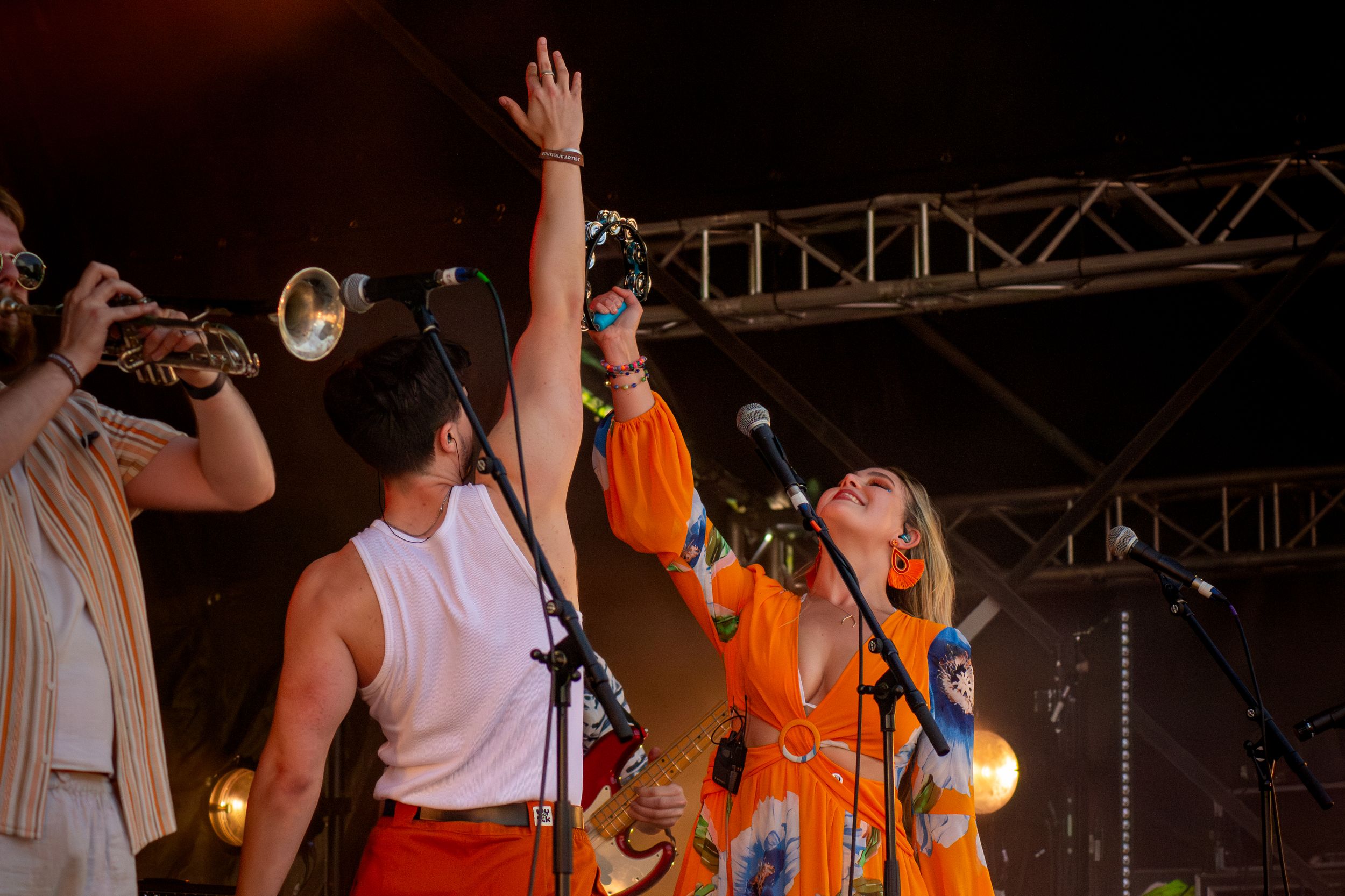 Band members performing together on stage with raised arms and instruments.