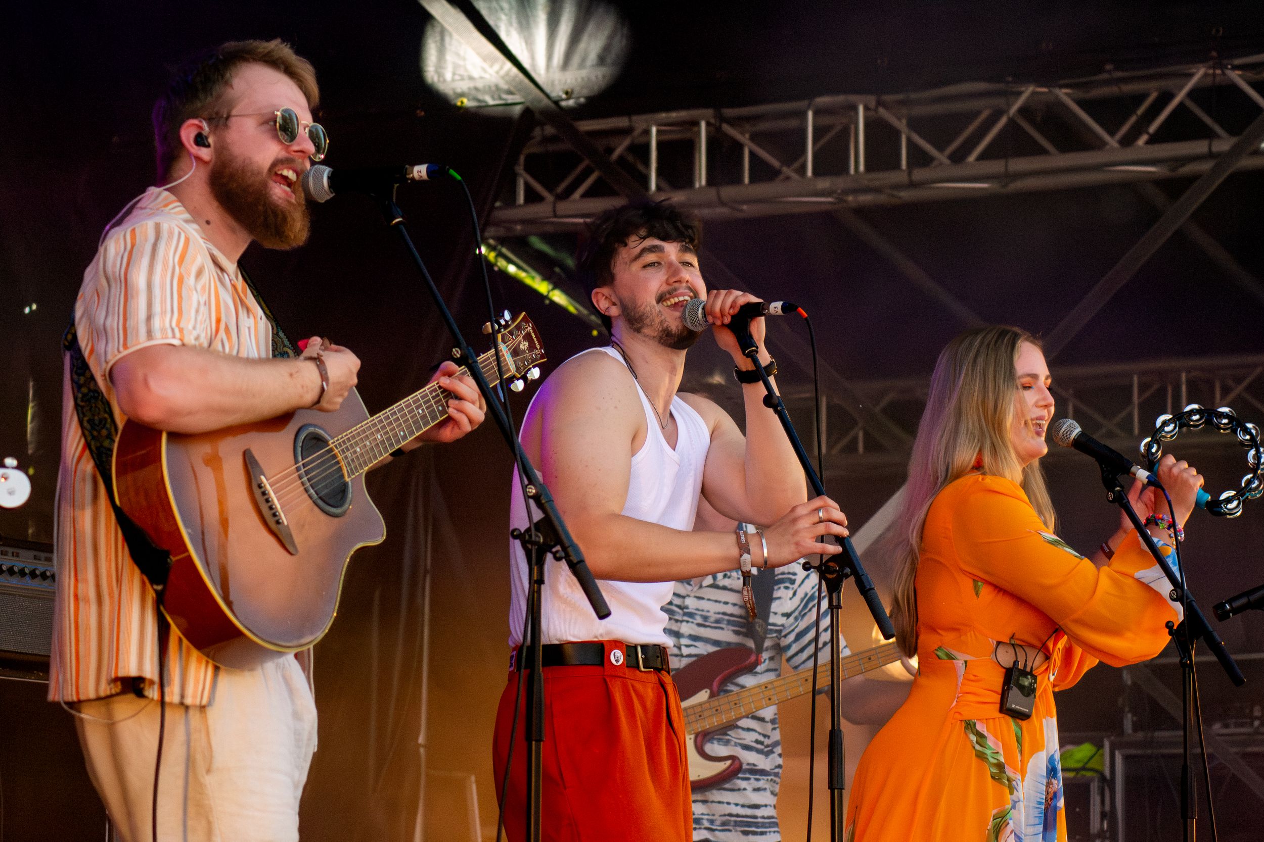 Band performing on stage with guitar, vocals, and orange floral dress ensemble.