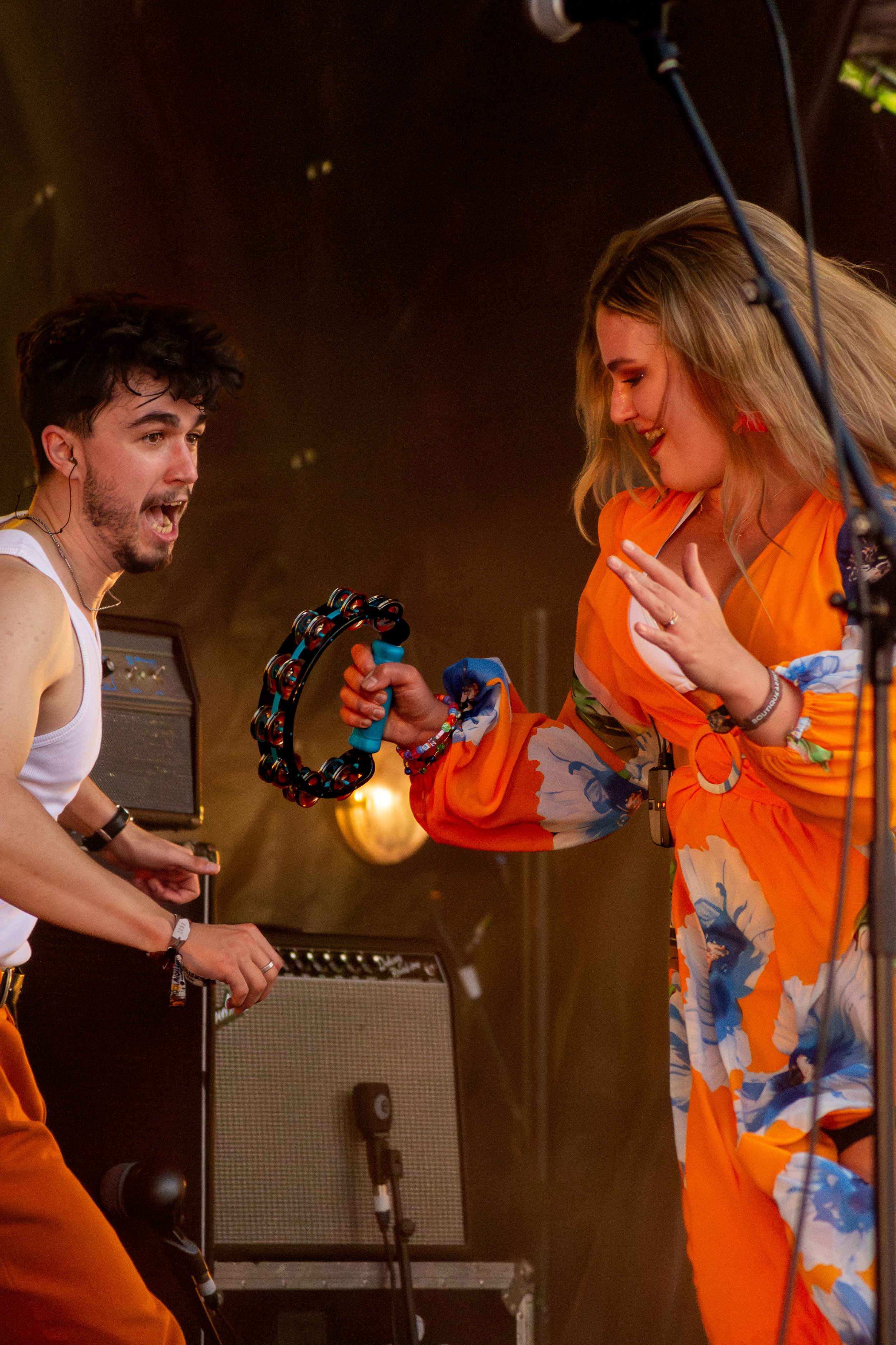 Musicians performing energetically on stage with tambourine and bright stage lighting.