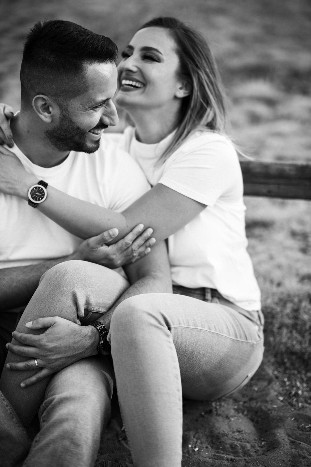 Black and white photo capturing an intimate moment of a couple laughing and embracing.