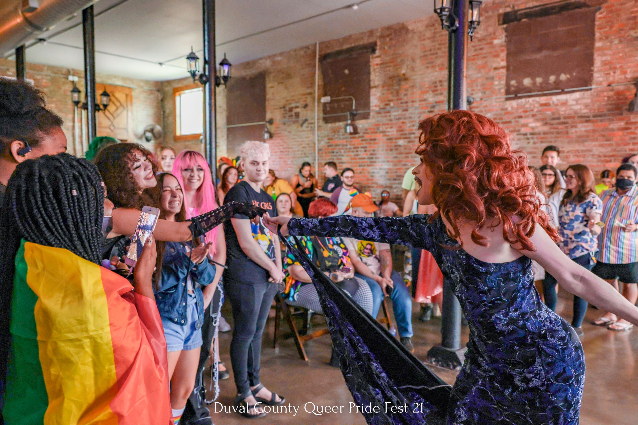 Entertainment show with audience and pride flag in historic brick venue.