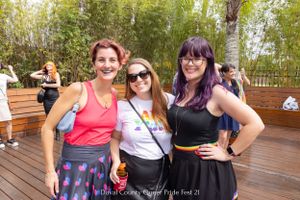 Three friends pose together on a wooden deck with bamboo plants in the background.