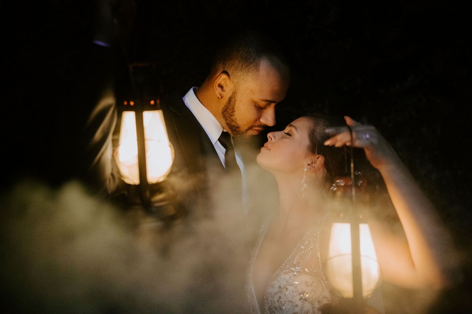 Romantic couple illuminated by lantern light in an intimate nighttime moment.