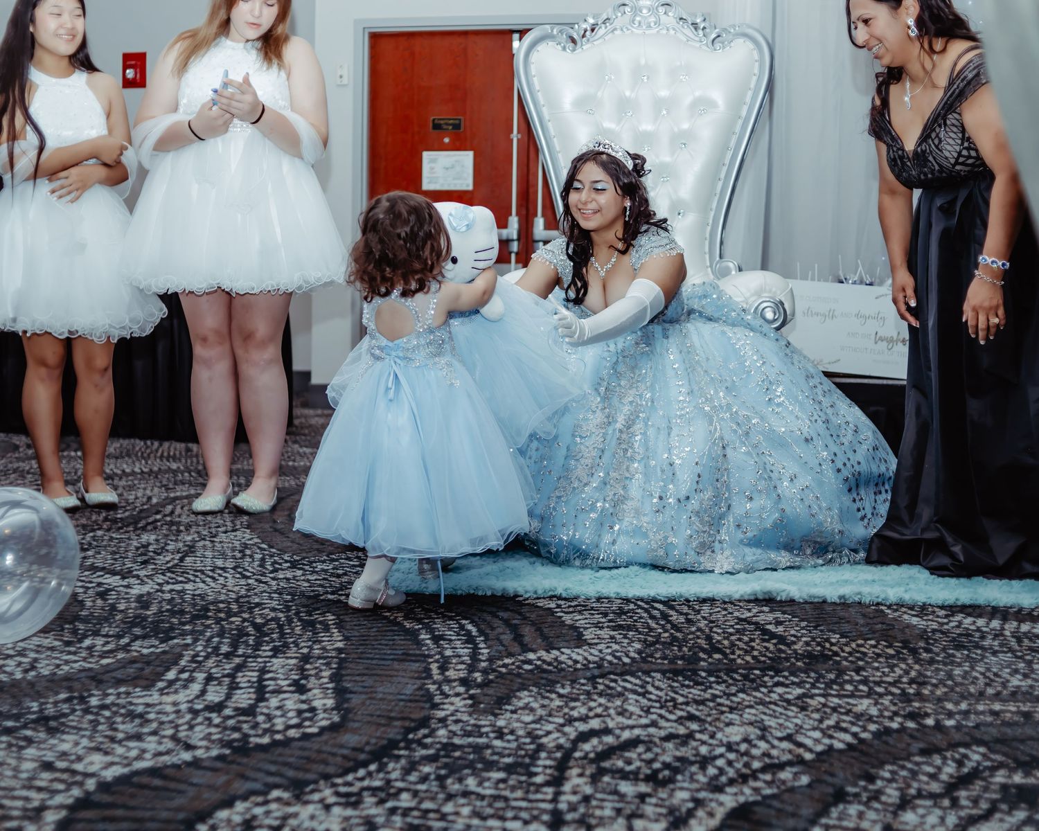 A celebration scene with formal dresses in shades of white, blue and silver against ornate backdrop.