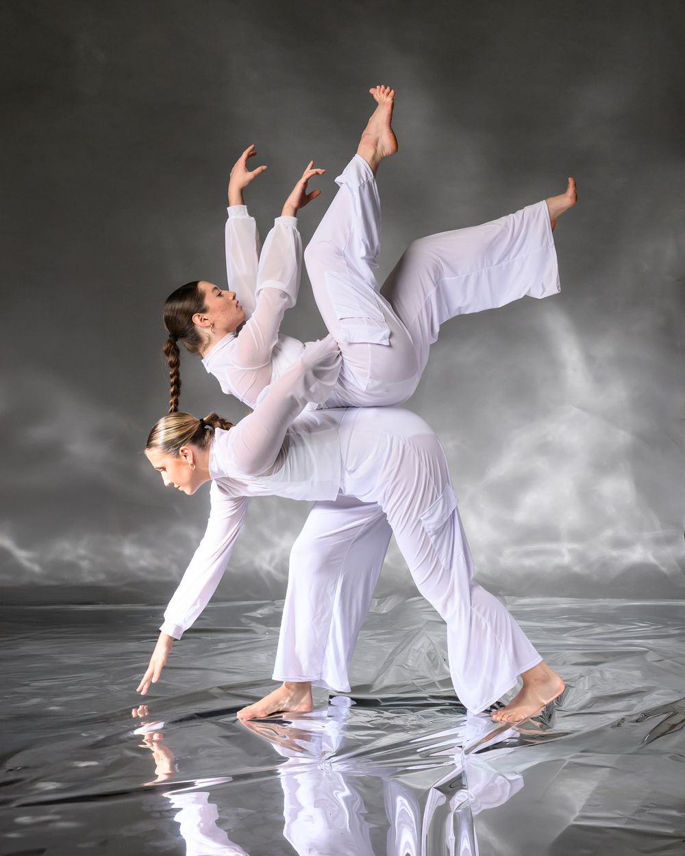 Dancer in flowing white attire performs a graceful sequence of contemporary dance movements against a dramatic dark background.