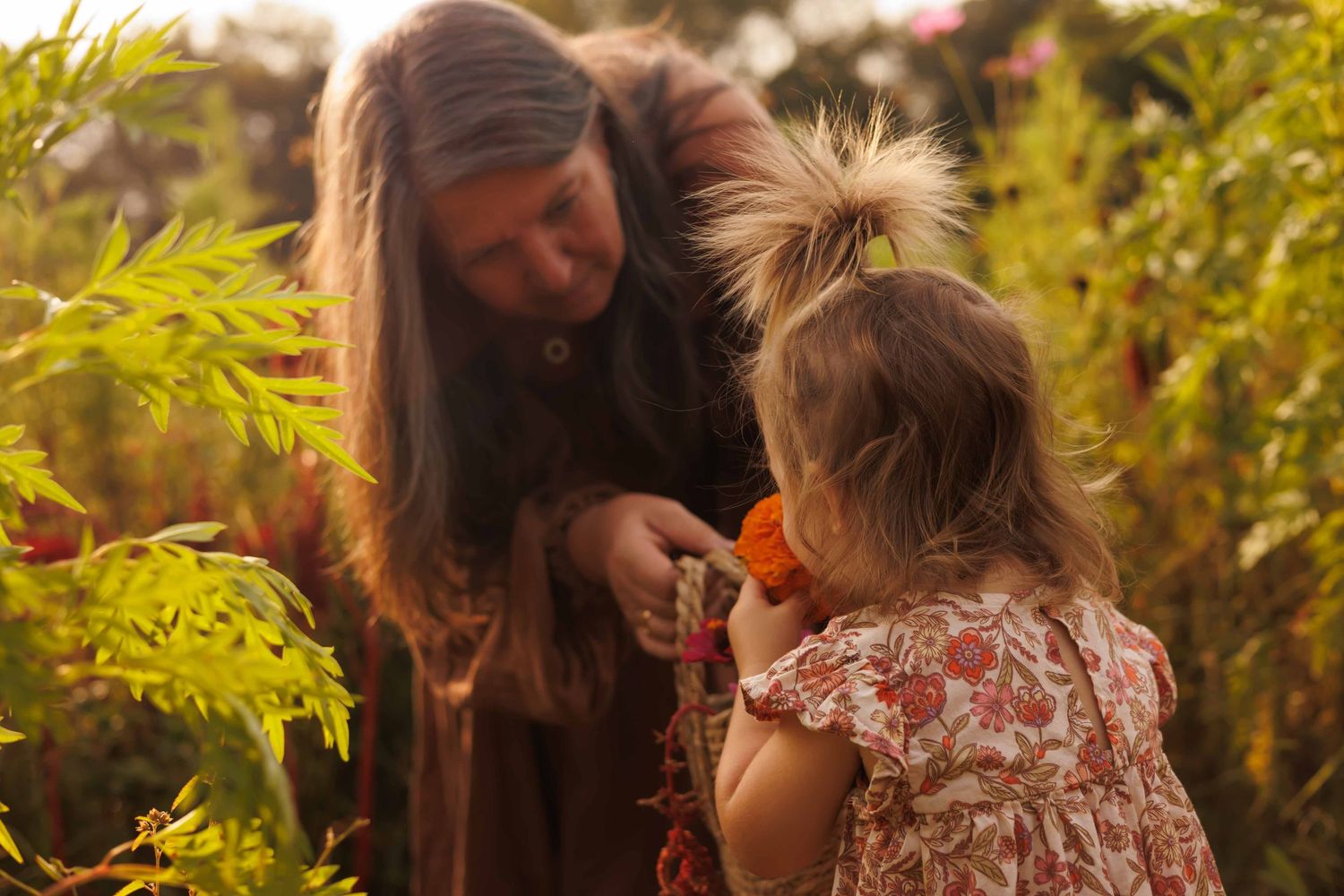 Mother and daughter sharing intimate moment among lush greenery outdoors.