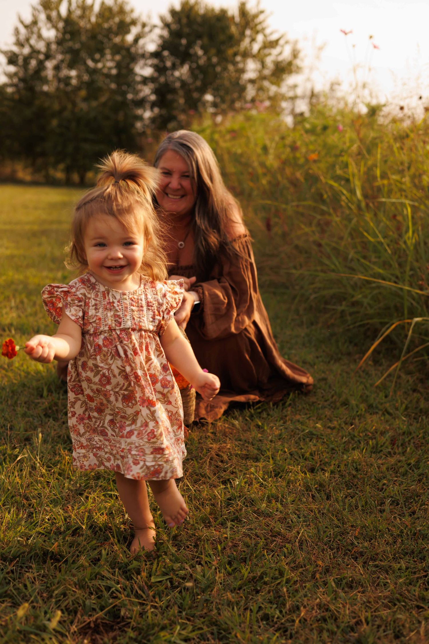 A playful moment captured in warm evening light with flowers and grass.