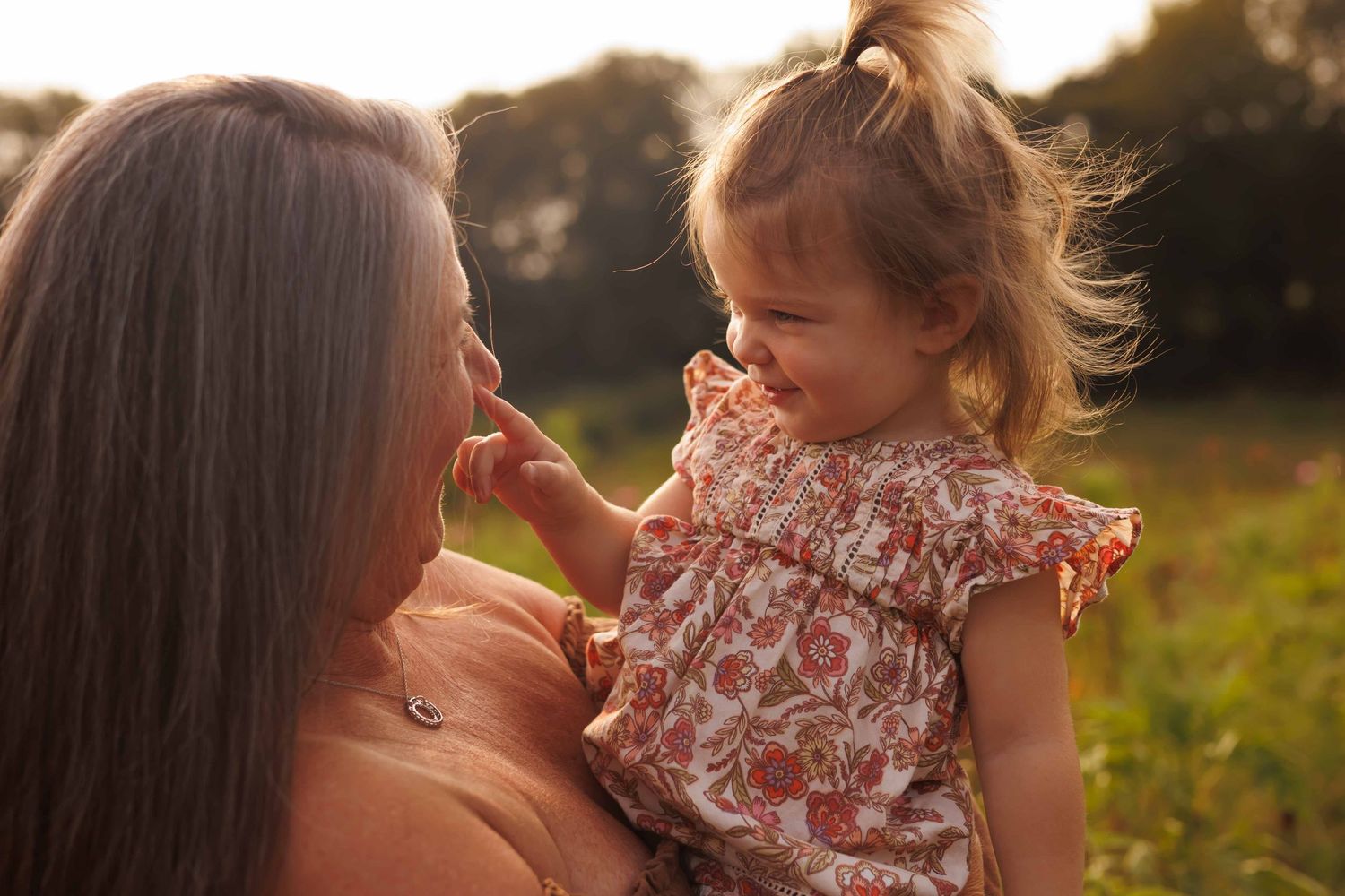Mother and child share tender moment together in sunlit meadow.