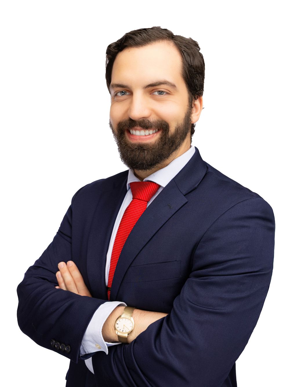 Professional businessman in navy suit and red tie smiles confidently with arms crossed.