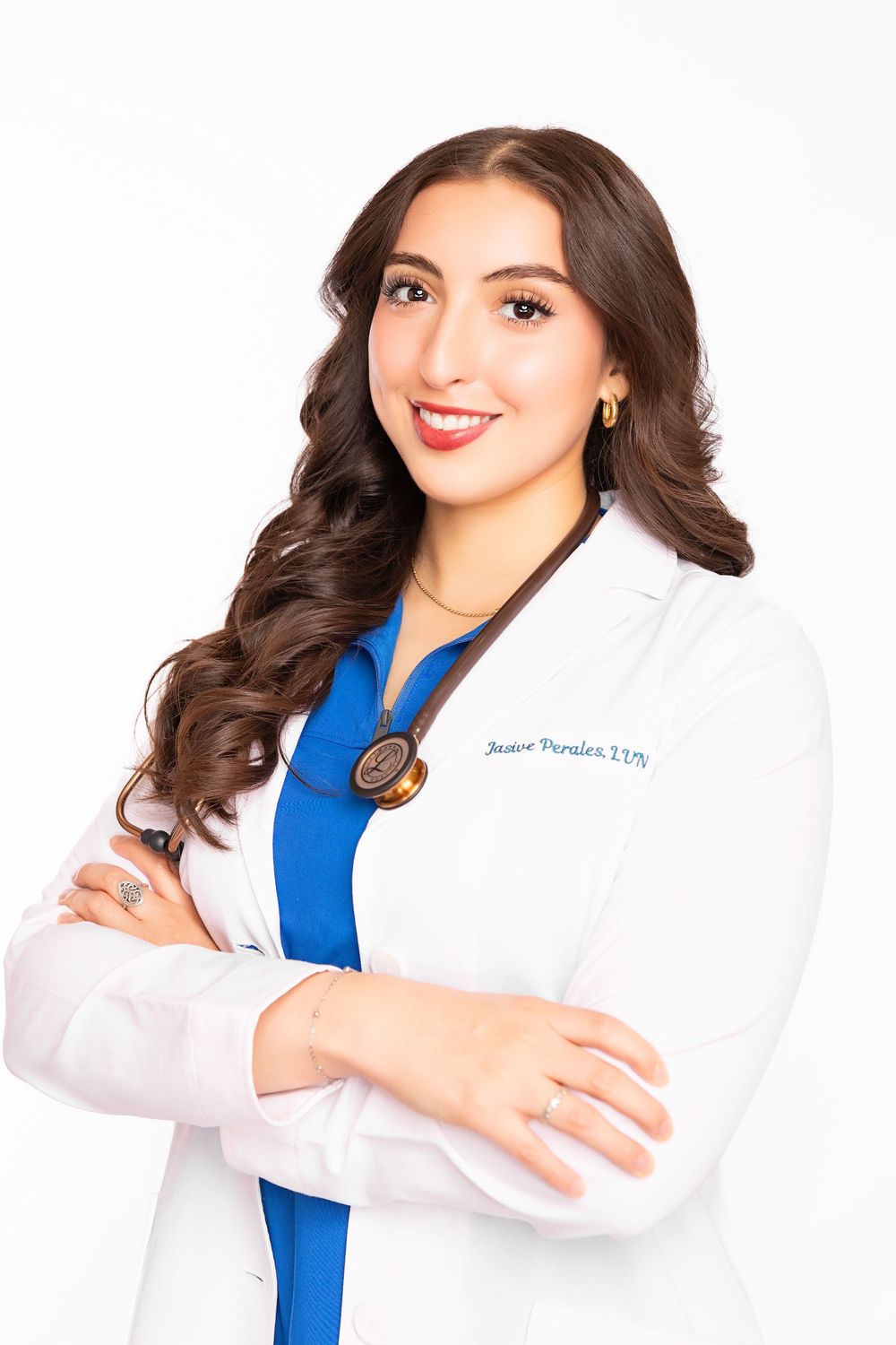 Healthcare professional in white coat and blue blouse posing with crossed arms in professional headshots.