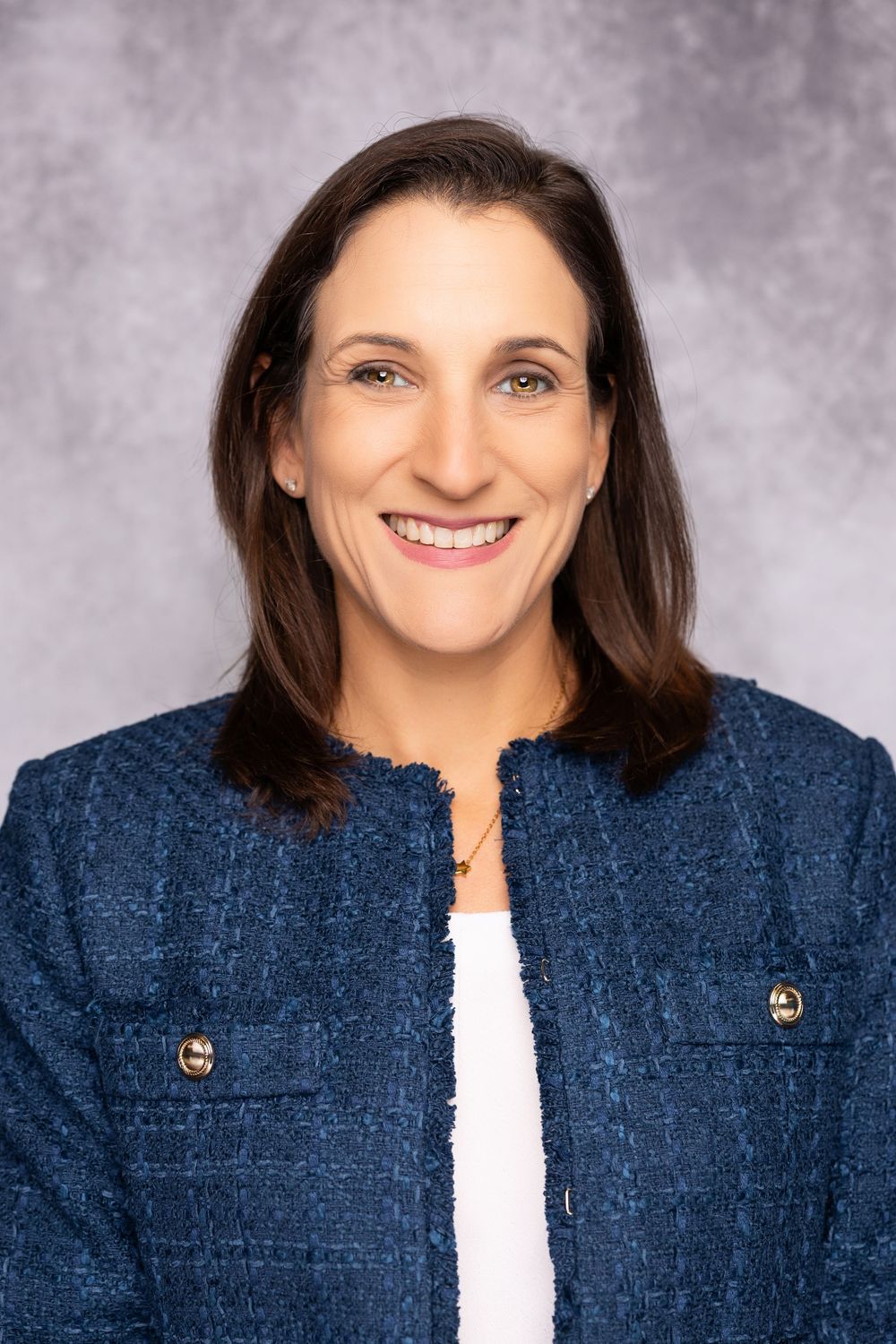 Professional headshot series showing a person in a navy blue textured jacket against a gray studio backdrop.