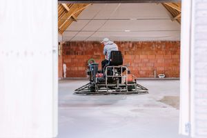 Professional concrete grinding machine in action on a construction site with brick wall background.