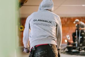 A person wearing a white t-shirt with text working in what appears to be an indoor commercial or retail space.
