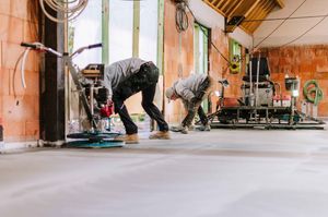 People working out and stretching in a gym with wooden floors and exposed brick walls.