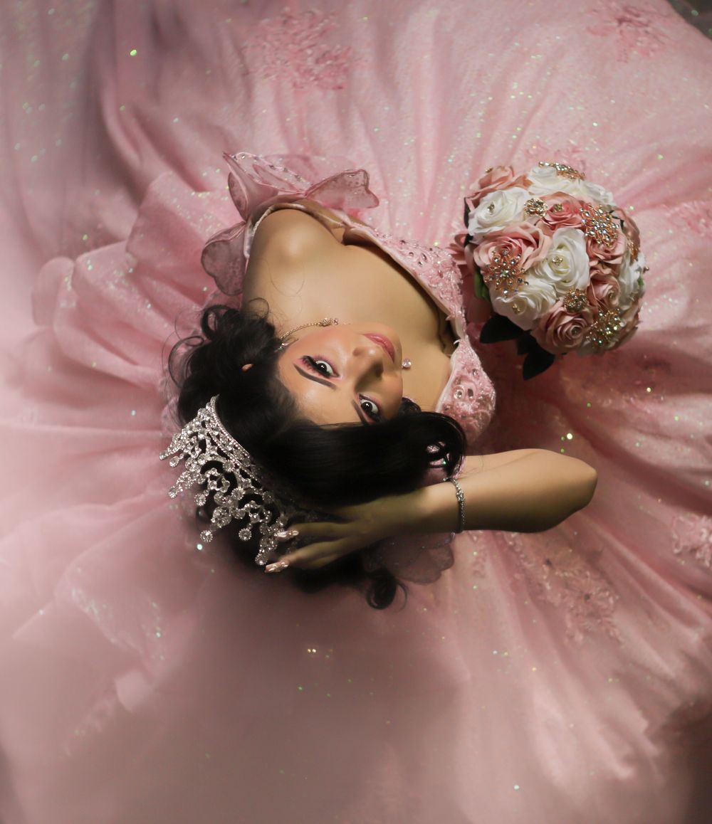 Someone lying in a flowing pink tulle gown with a decorative bouquet of flowers nearby.