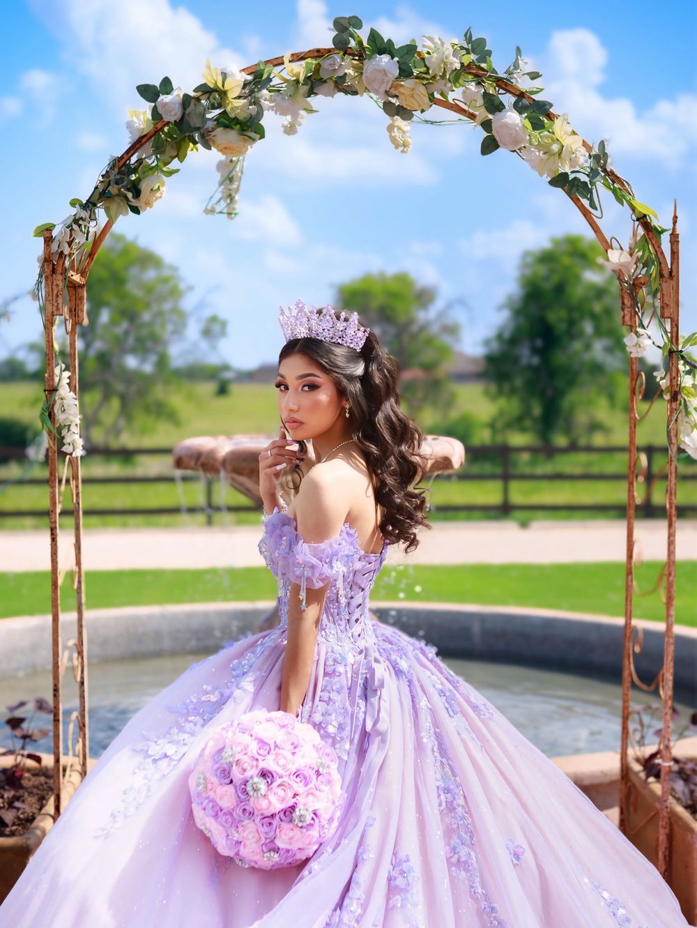 Lavender quinceañera dress showcased in outdoor photo session with floral arch and natural backdrop.