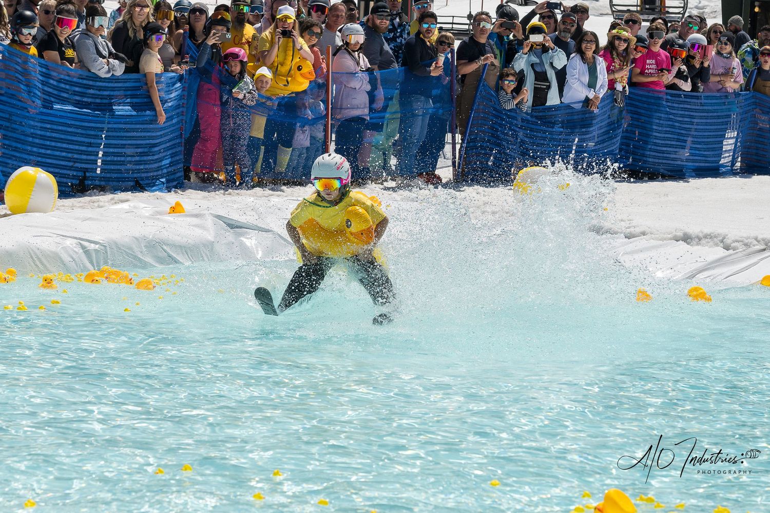 People enjoying a water park with colorful floating objects and splashing in a pool.