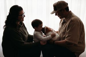 Silhouette of 4 people in tender family moment together against bright window background.