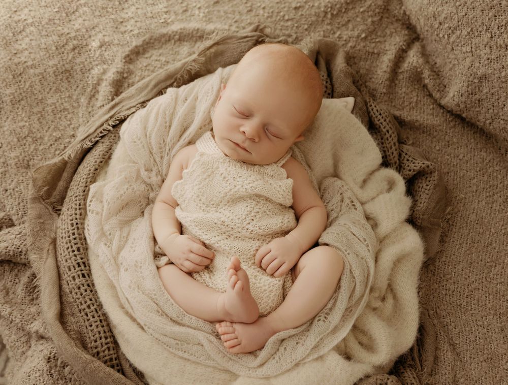 newborn boy wrapped in brown and cream blankets duing his newborn photoshoot