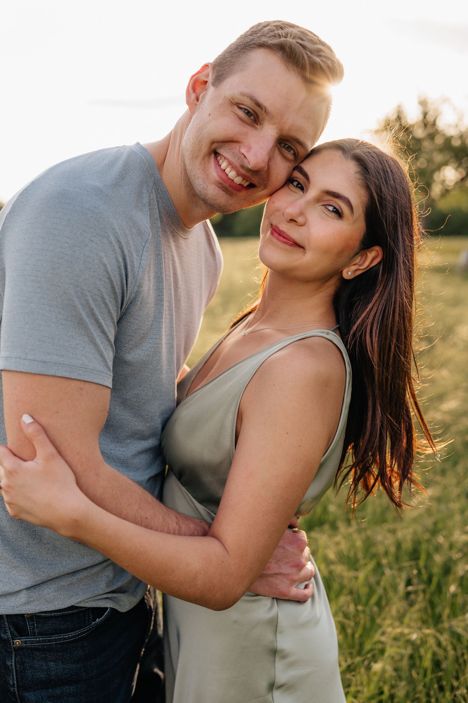 Intimate portrait of couple embracing in casual wear against natural outdoor backdrop.