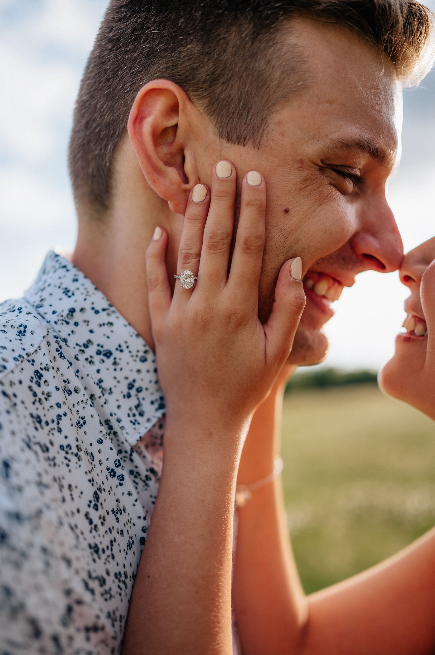 Close-up of joyful interaction between couple with hands on face in outdoor setting.