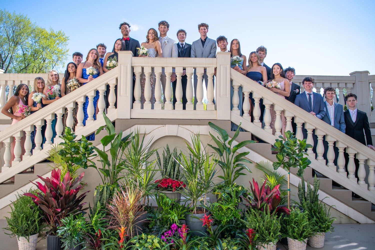 A group poses with blue and white balloons for a formal event celebration.