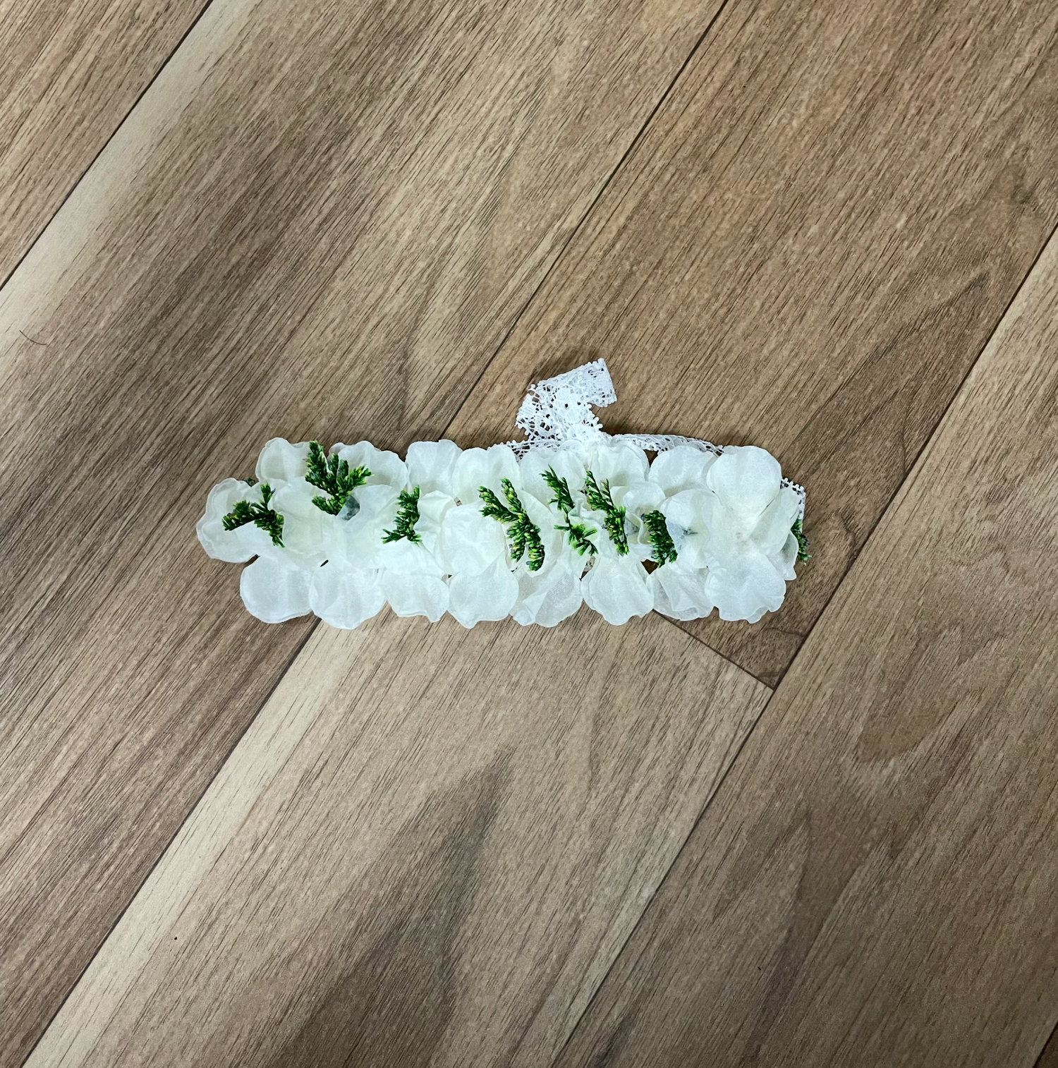 White floral garland displayed in different arrangements on hardwood flooring.