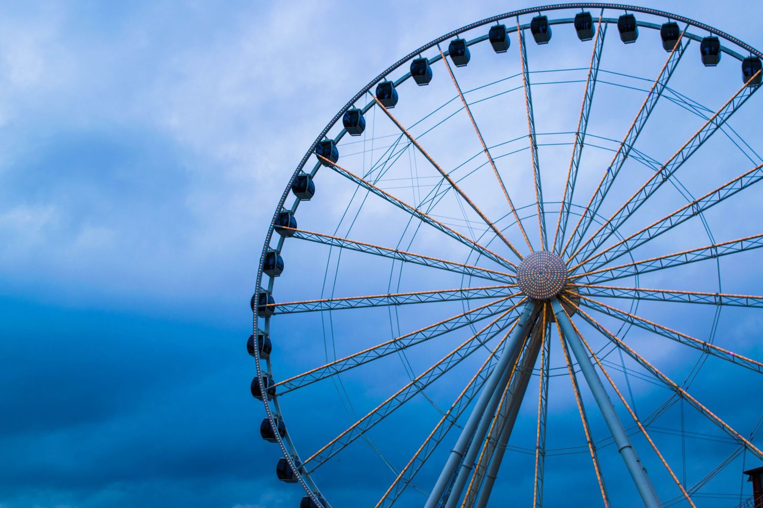 Large Ferris wheel silhouetted against a blue cloudy sky at dusk.