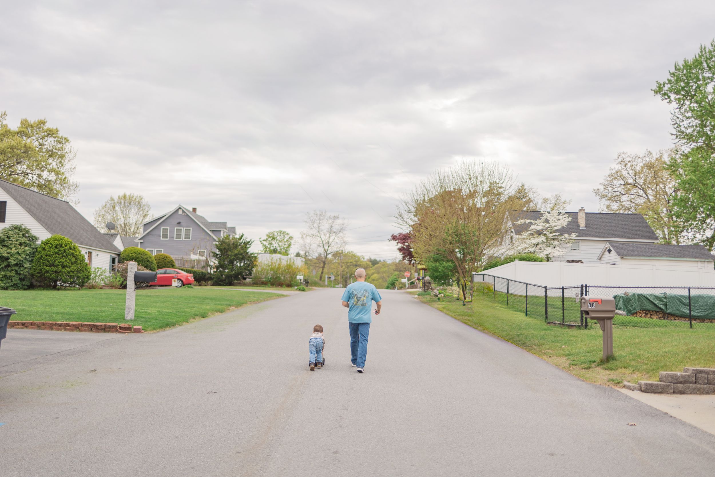 Two people walking down a suburban street on an overcast spring day.