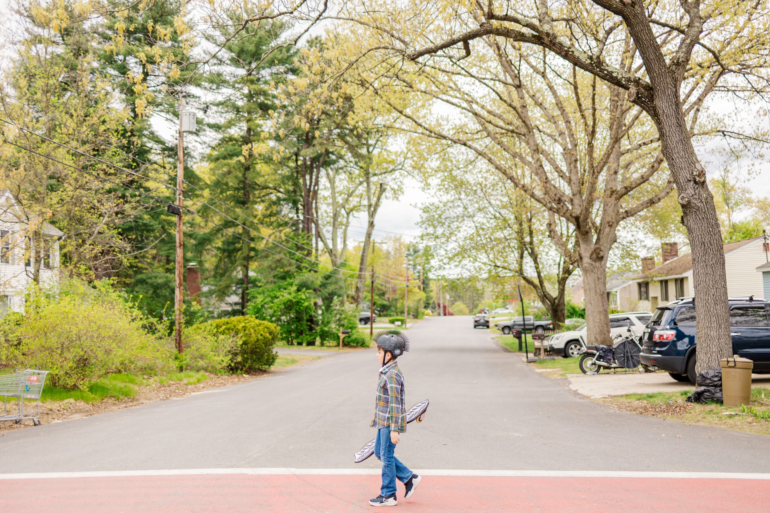 Person walking down a tree-lined residential street during spring.