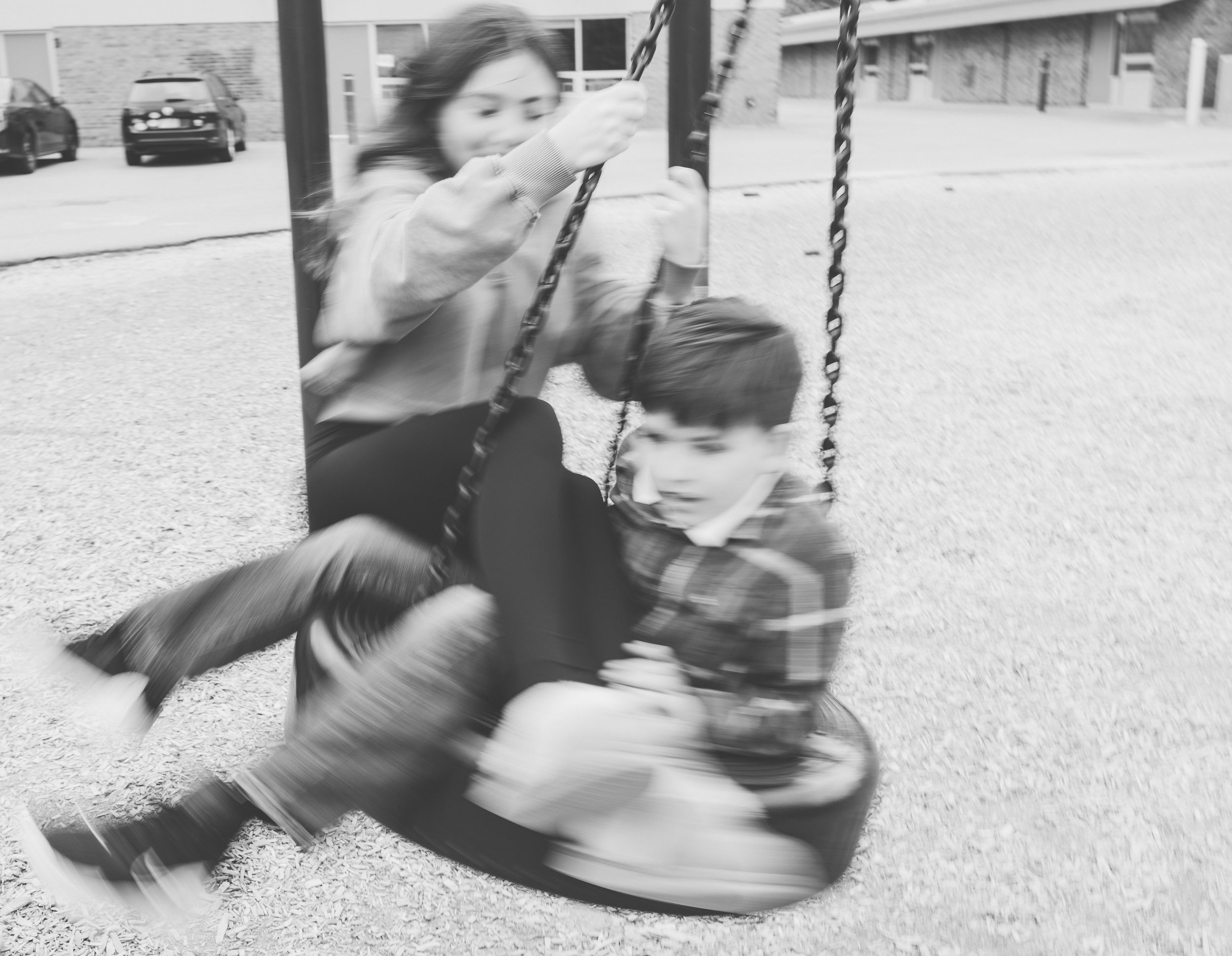Black and white photo of people enjoying a swing set in motion.