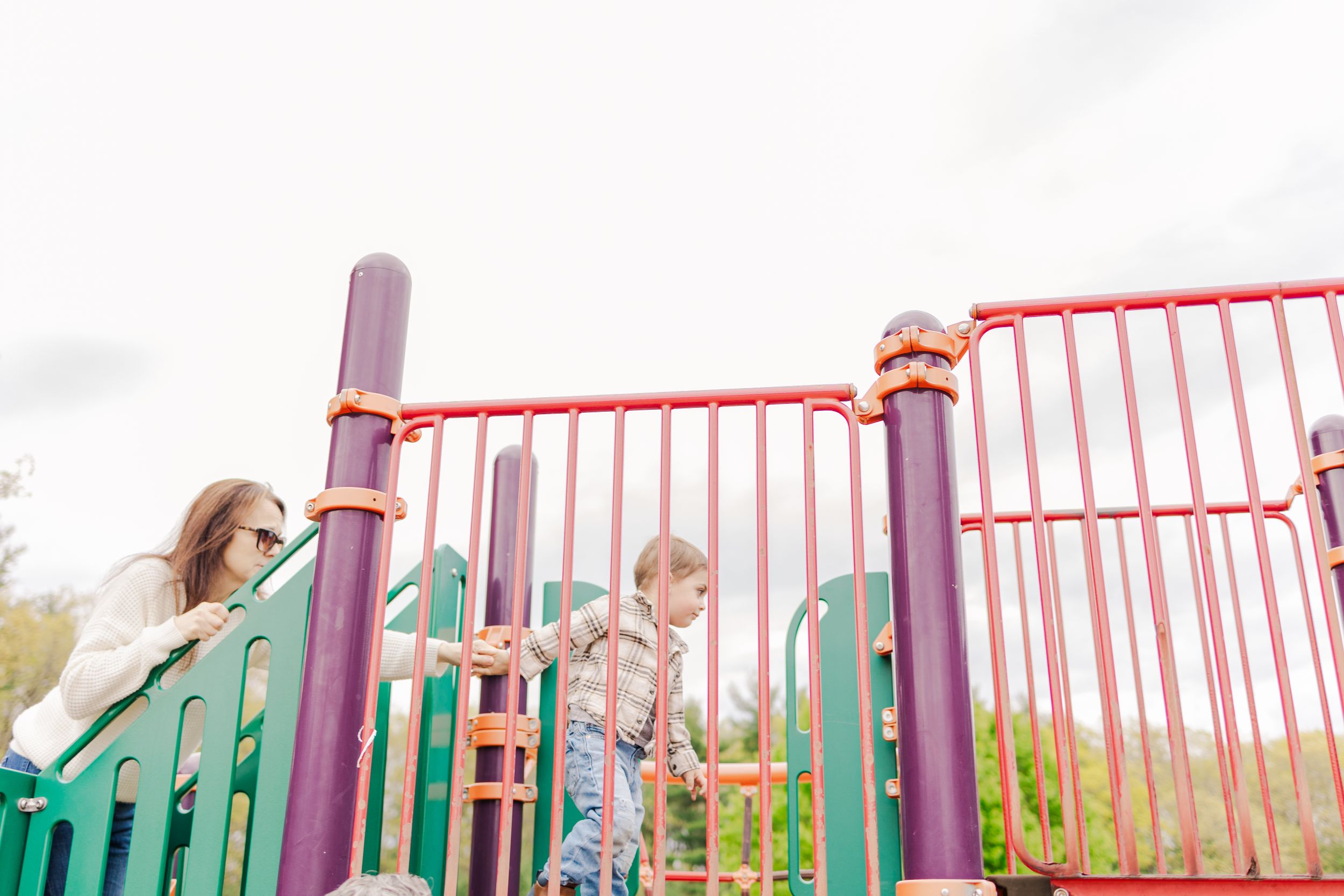 Children climbing and playing on colorful playground equipment on a bright day.