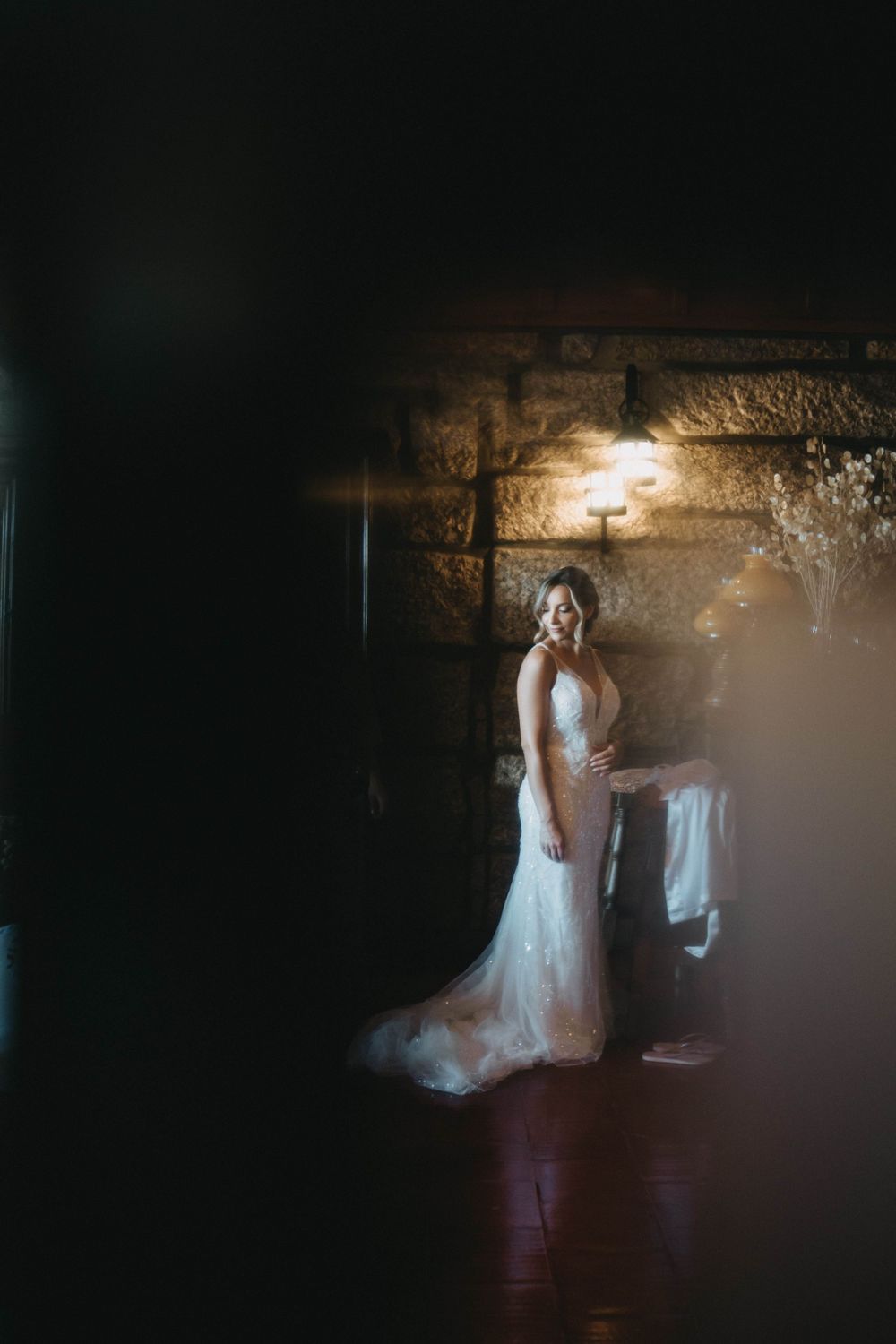 Moody bridal portrait with dramatic lighting against stone wall backdrop.