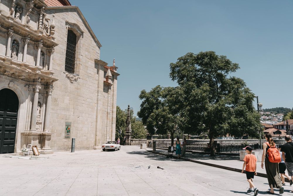Historic stone church exterior with plaza and pedestrians on sunny day.