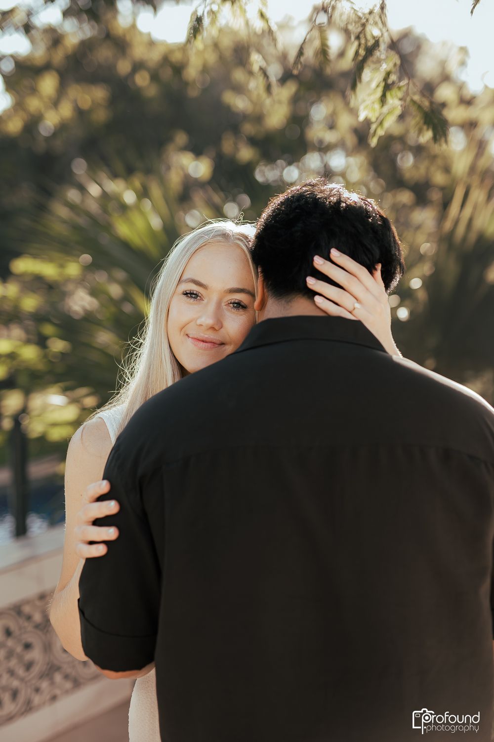 Tender moment captured between couple during outdoor photoshoot with natural sunlight.