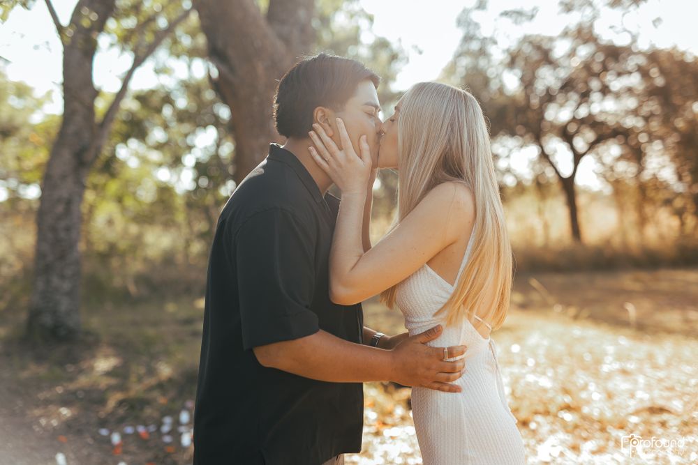 Intimate embrace between couple during romantic outdoor photoshoot at sunset.