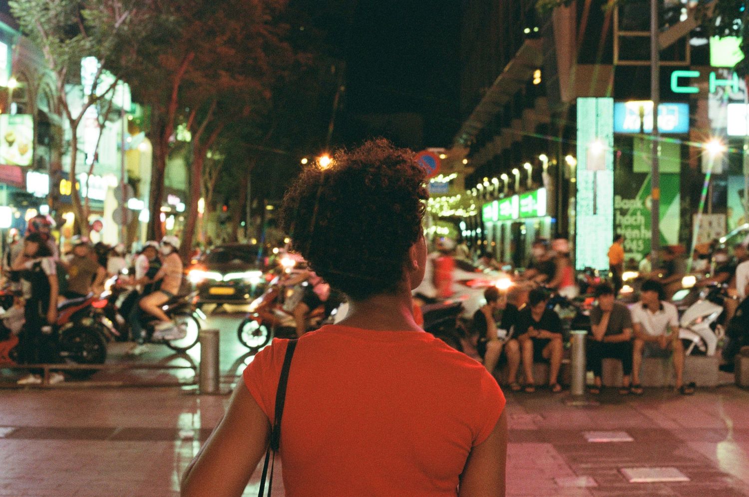 A bustling nighttime city street scene with crowds and lights in an urban setting.